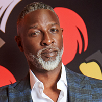 Headshot of a middle-aged black man with a beard against an abstract background.