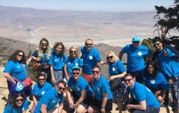 Group photo in matching blue shirts in front of a desert landscape